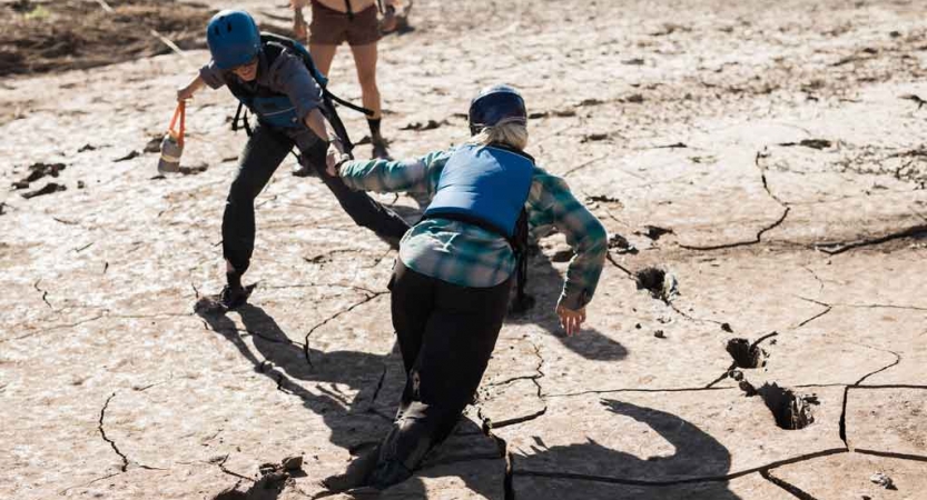 a student helps another who is stuck in mud